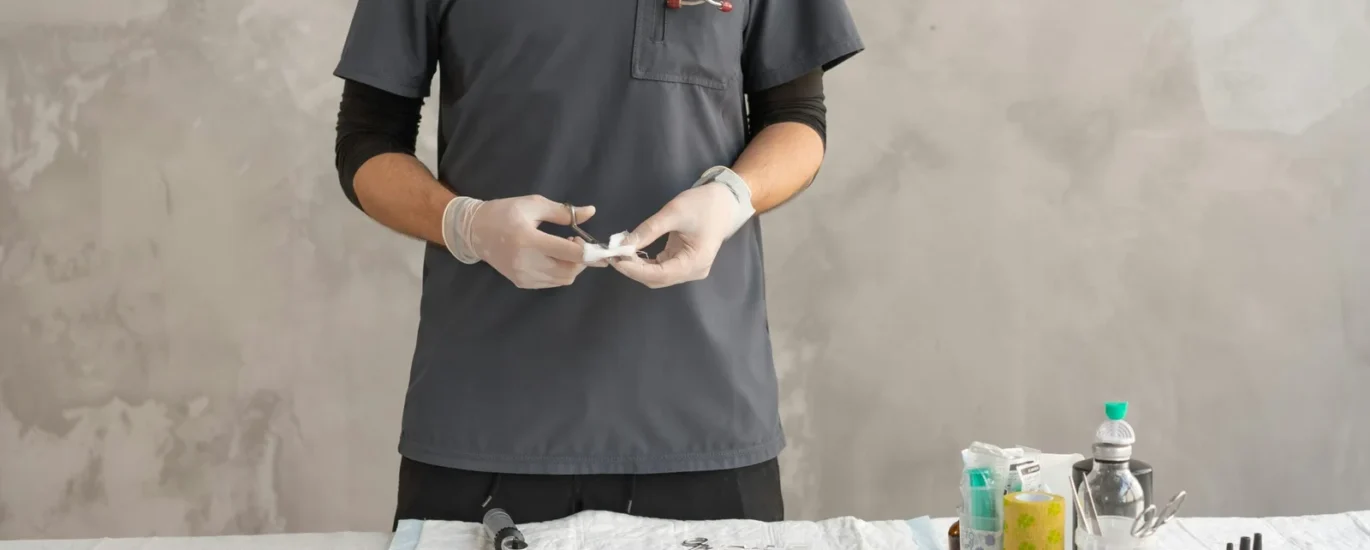 Healthcare professional in gloves preparing medical supplies on a table, showcasing a sterile environment and readiness for patient care.