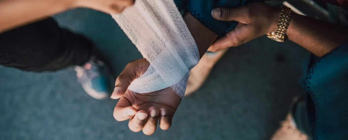 Person applying a white bandage to a patient's arm, highlighting advanced wound care techniques in a clinical setting.