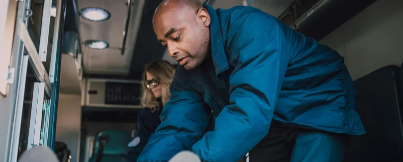 Emergency medical technician assisting patient in ambulance, focused on care and support.