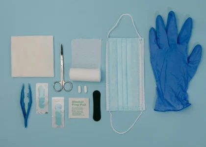 Medical supplies for wound care including gloves, mask, scissors, alcohol prep pads, and gauze on a blue background.