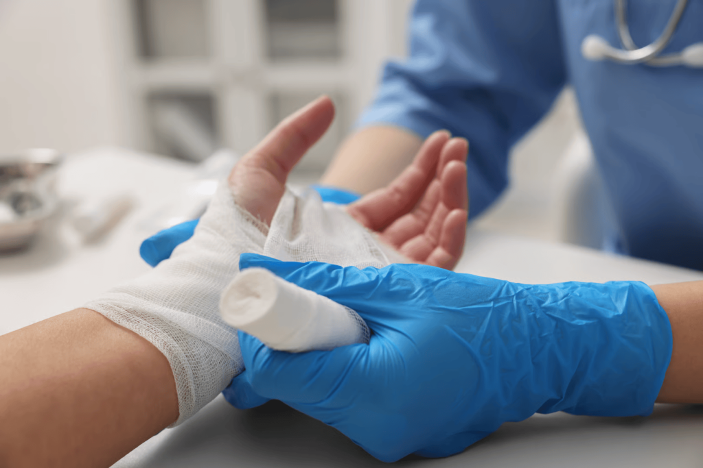 Healthcare professional in blue gloves applying a bandage to a patient's injured hand, illustrating advanced wound care and regenerative medicine practices.