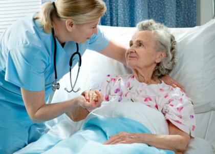 Nurse comforting elderly patient in hospital bed, highlighting compassionate care in wound healing and prevention of sacral ulcers.