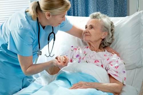 Nurse comforting elderly patient in hospital bed, emphasizing compassionate care for preventing pressure sores.